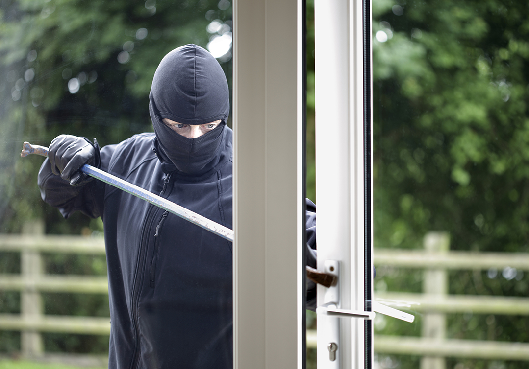 Burglar breaking into a house window with a crowbar